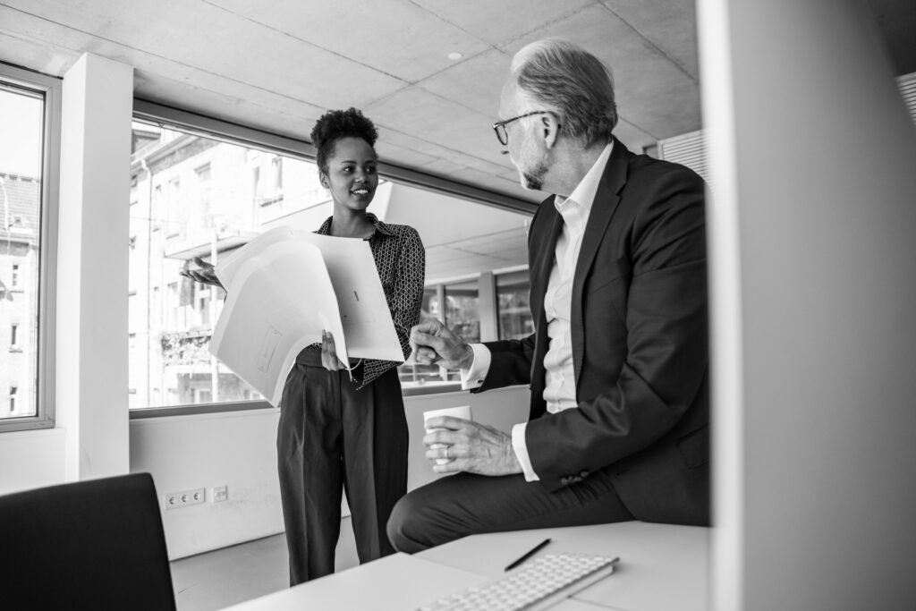 Photo of two people having a discussion in an office while holding some papers
